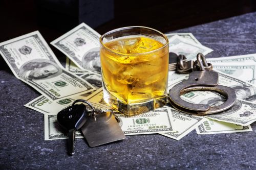 Car keys, alcohol, dollars and handcuffs to illustrate that you will go to jail if you dink and drive. DWI charges concept.