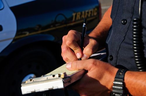 A police office on the side of the road as he writes a ticket - traffic ticket points concept