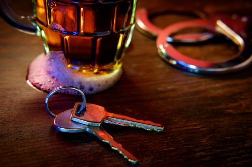 Mug of frothy beer with handcuffs and keys - dui aggravating factors concept