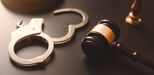 Handcuffs and wooden gavel. difference between a misdemeanor and a felony concept